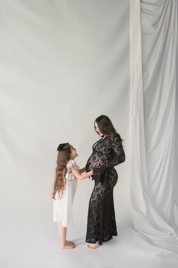 Pregnant woman and daughter sharing a tender moment in studio.